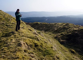 Archaeologist standing on grass covered ramparts