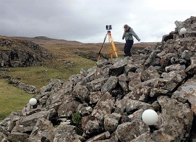 Archaeologist with a tripod standing on fallen stones