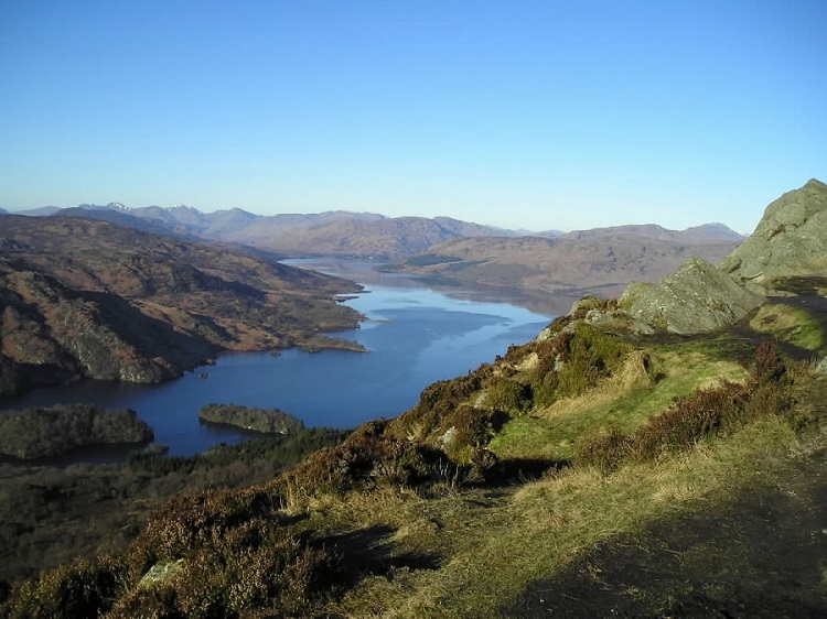 View from craggy hillside over calm blue loch