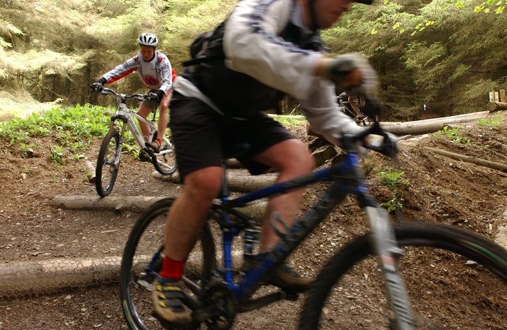 Two people on mountain bikes negotiating a sharp corner on an off-road track