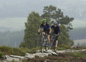 Two mountain bikers riding on a raised rocky trail