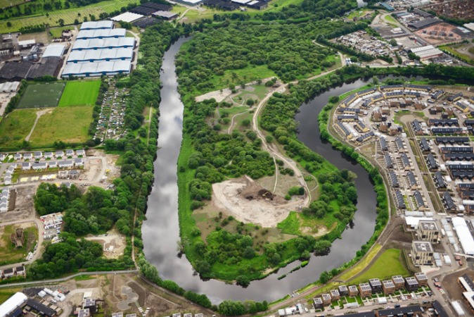 Aerial view of mixed use ground showing river, trees and urban environment