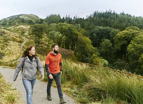 Man and woman walking along a path away from a hilltop