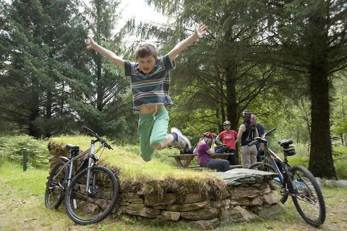 Young boy jumping in the air with bikes and family members in the background