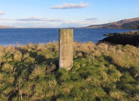 A concrete triangulation point on a grassy headland