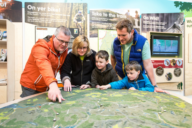 Family in visitor centre looking at model map