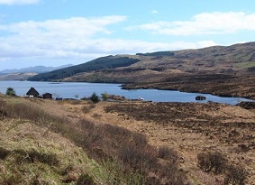 A view across rough moorland towards a loch