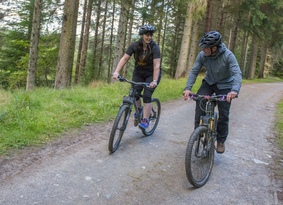 Two people cycling along a woodland path