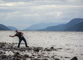 Man skimming stones on a loch