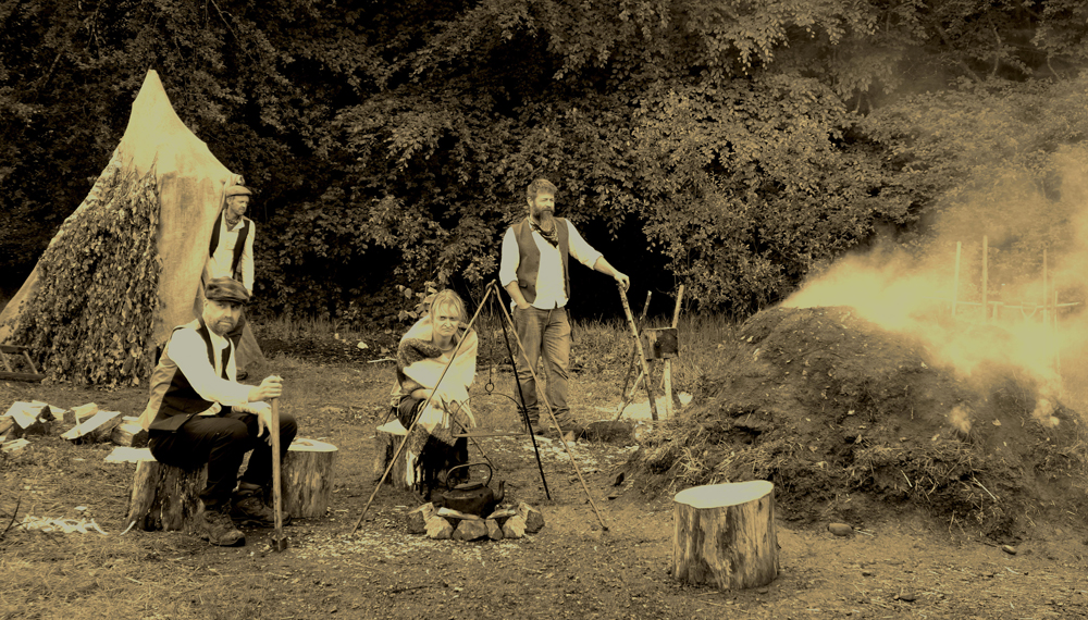 Sepia style photograph of several people around a large smouldering mound