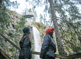 Two girls looking towards a very tall waterfall