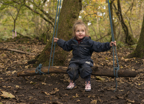 Young girl sitting on a swing made from a branch