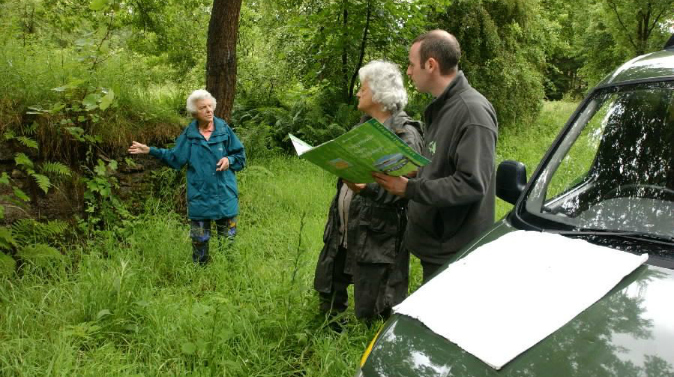 Staff members standing by a car with a map, while observing the habitat. 