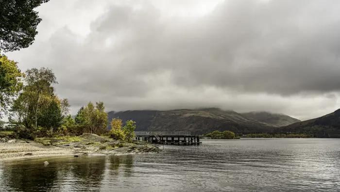 Loch with tree line shore and a jetty.