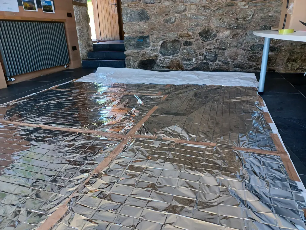 A large silver sheet covering trees inside a stone building.