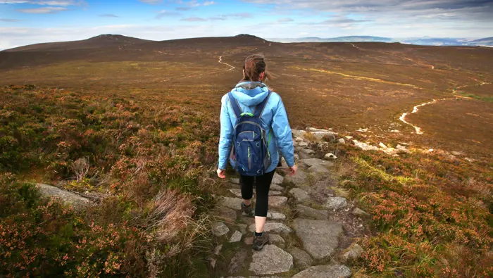 Person walking downhill along a footpath.