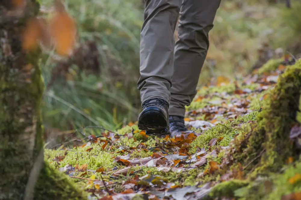 Man's feet walking on autumn leaves