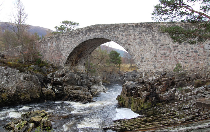 A stone bridge at Little Garve, under which there is fast flowing white water between rocks.