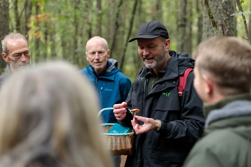 Person holding a fungus with people gathered around.