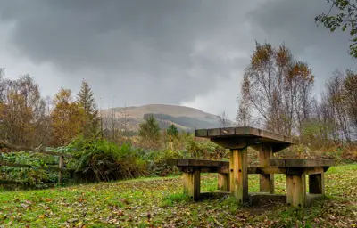A picnic table with mountains and autumn trees behind it