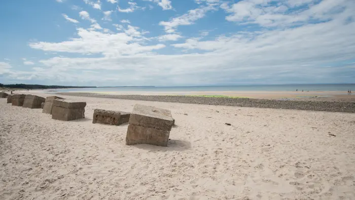 Concrete tank barricades lining a white sand beach