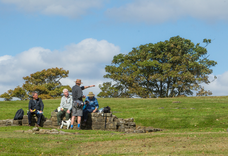 A group of people stopping for lunch while out walking with a dog