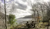 A wooden picnic table overlooking a loch