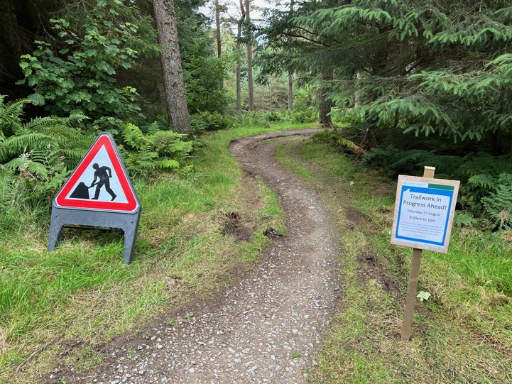 A section of trail with signage. One indicating that work is being done to it. The other indicating that the Trailfairies volunteers will be working there that day.