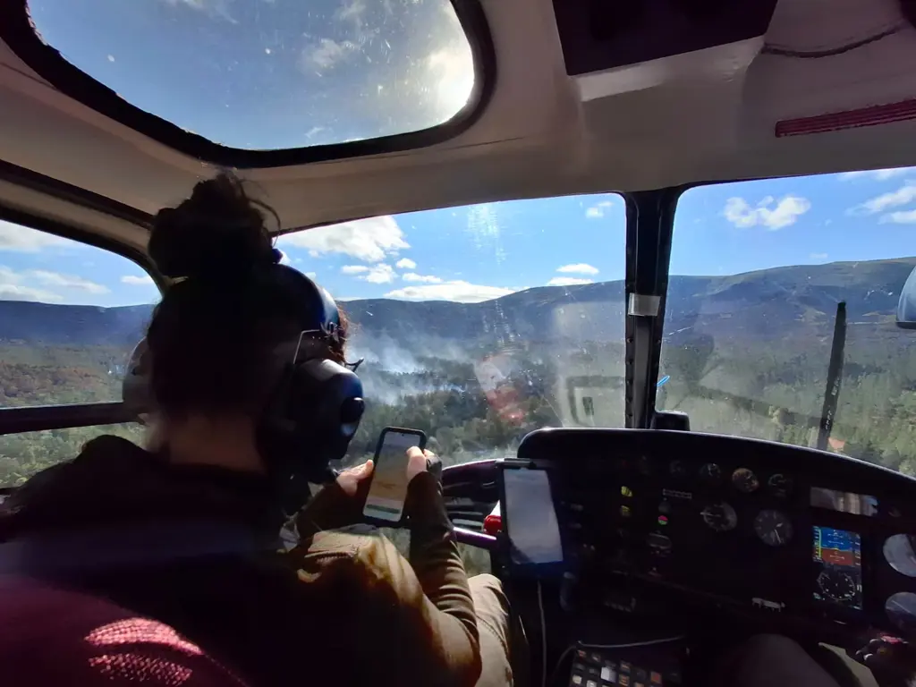 Person in helicopter with map displaying on their mobile device.