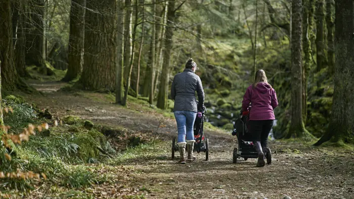 Two people with buggies on a footpath.