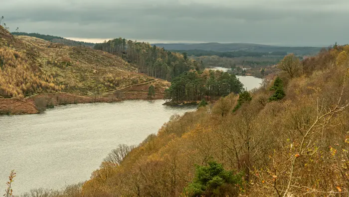 An island in a loch surrounded by trees and hills in autumn.