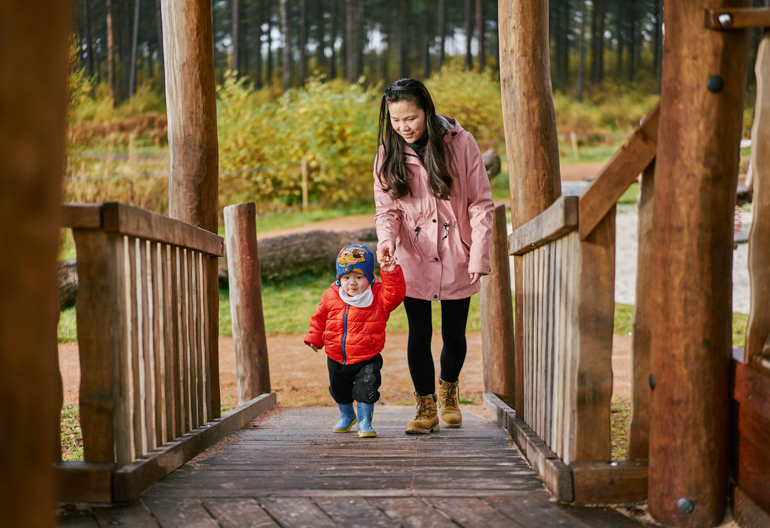 Woman and young boy walking across wooden bridge at Tentsmuir (near Leuchars) on forest trail