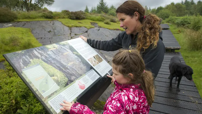 Adult and child looking at an interpretation board.